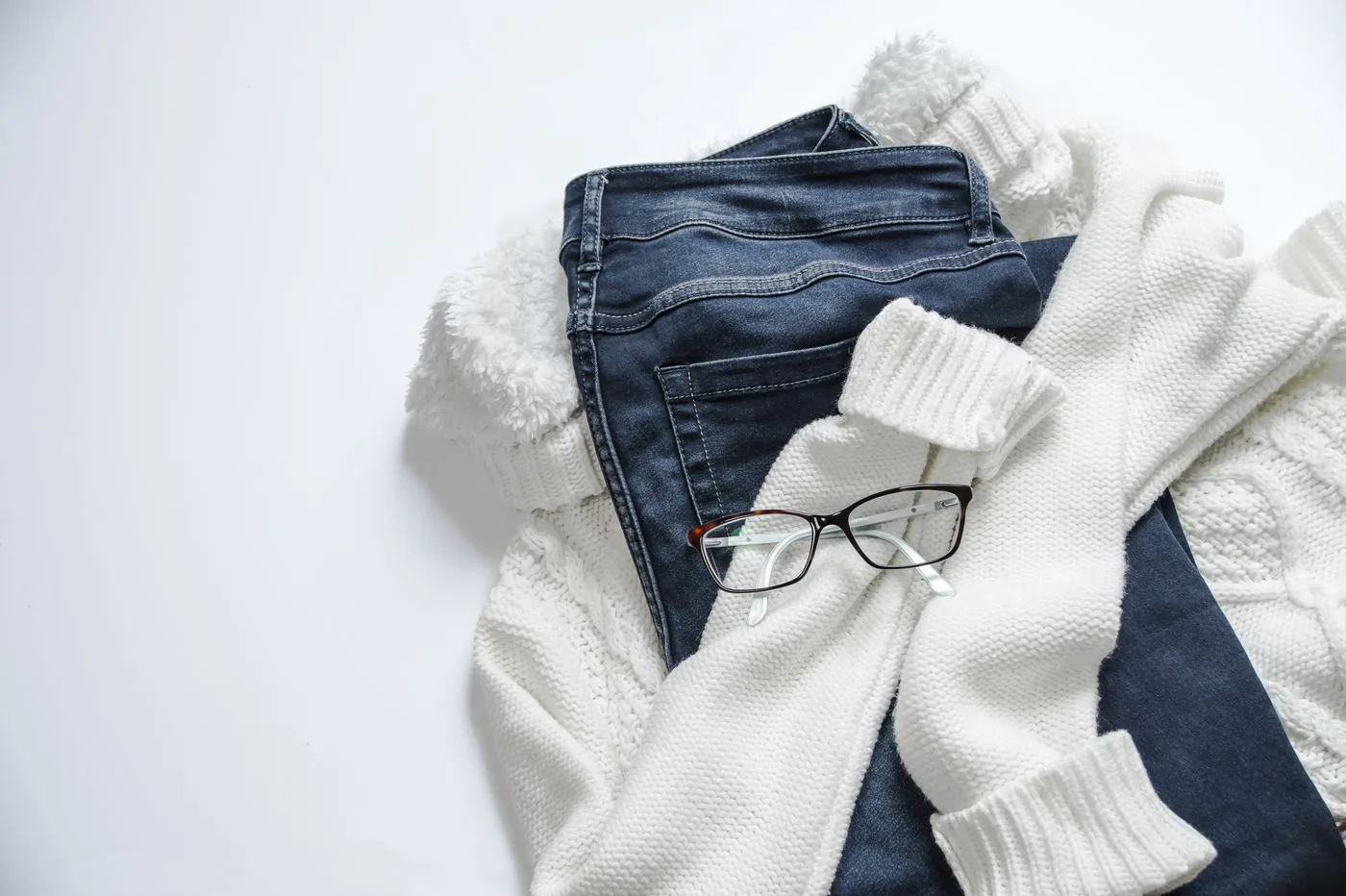 Jean, tricot blanc et lunettes disposés à plat